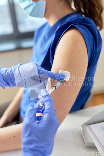 Image of doctor with syringe vaccinating medical worker