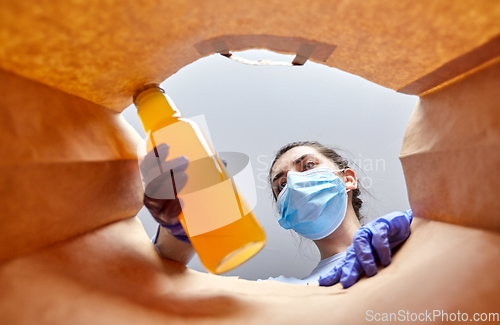 Image of woman in gloves and mask with food in paper bag