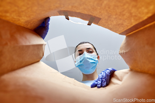 Image of woman in gloves and mask with food in paper bag