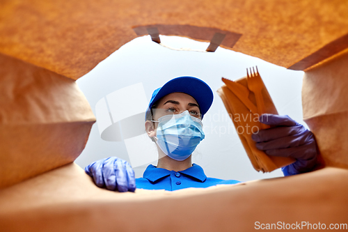 Image of delivery girl in gloves and mask with food in bag