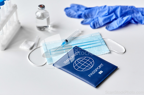 Image of immunity passport, mask, syringe, vaccine on table