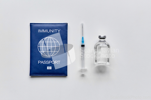 Image of immunity passport, syringe and vaccine on table