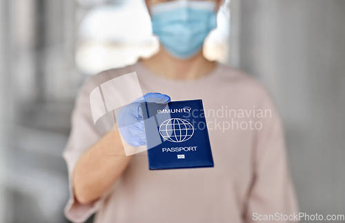 Image of woman in mask and gloves holding immunity passport