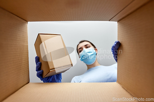 Image of woman in mask taking box from parcel