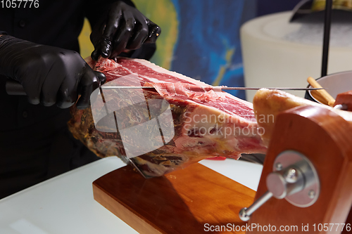 Image of Sliced dried chamon prosciutto. A man cuts a jamon, a warm toned image. Selective focus point.