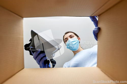 Image of woman in mask taking vr glasses out of parcel box