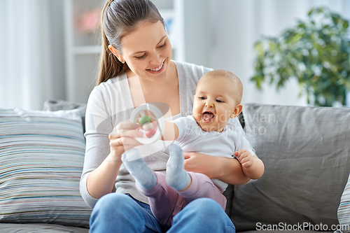 Image of mother and little baby playing with rattle at home