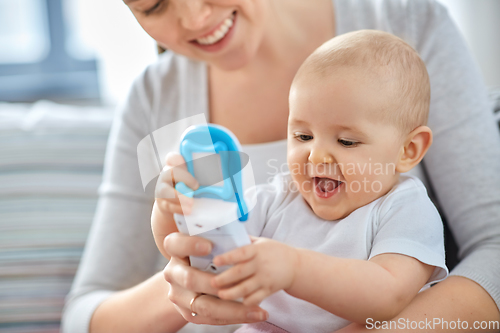 Image of mother with baby playing with toy phone at home