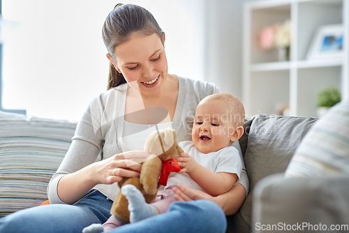 Image of mother with baby playing with teddy bear at home