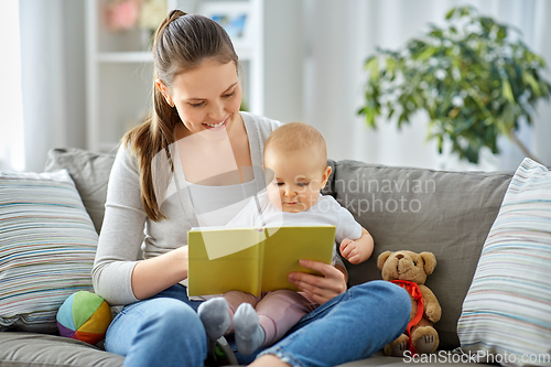 Image of happy mother reading book to little baby at home