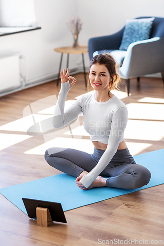 Image of young woman with tablet pc doing yoga at home