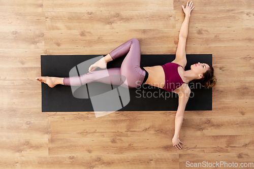 Image of woman doing yoga and stretching on floor at studio