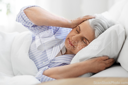 Image of annoyed senior woman with headache in bed at home