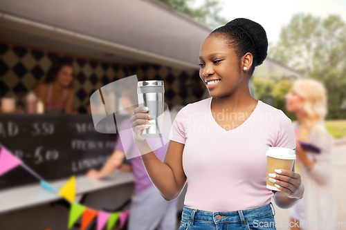 Image of woman with coffee cup and tumbler over food truck