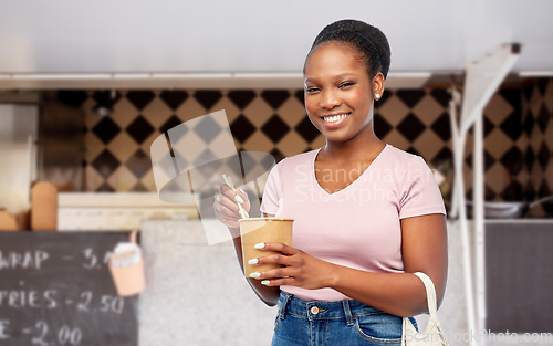 Image of happy woman eating wok over food truck