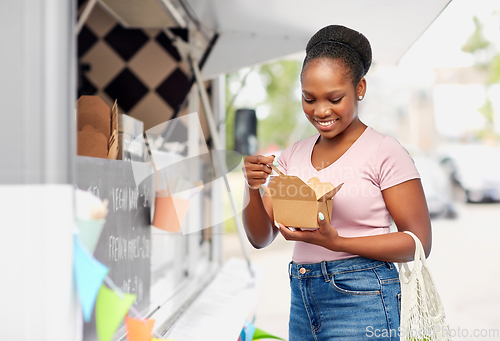 Image of happy woman eating wok over food truck