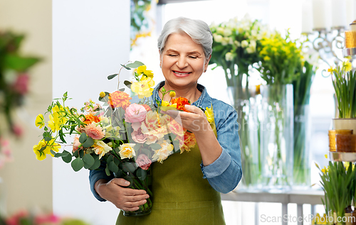 Image of smiling senior woman in garden apron with flowers