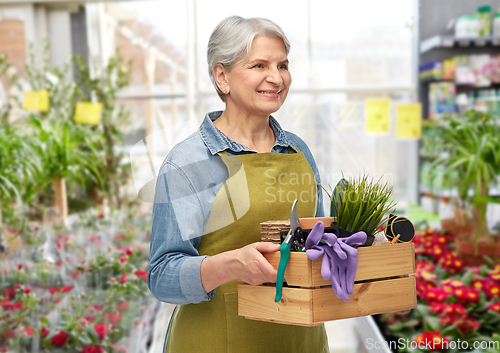 Image of smiling senior woman with garden tools in box