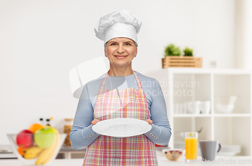 Image of smiling senior woman or chef holding empty plate