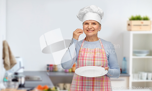 Image of smiling senior woman or chef holding empty plate