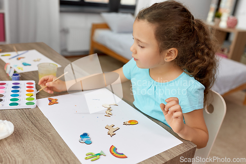 Image of little girl painting wooden items at home