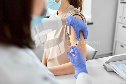 Image of female doctor with syringe vaccinating patient