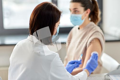 Image of female doctor with syringe vaccinating patient