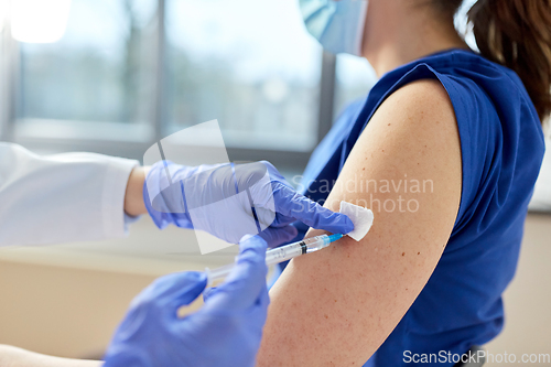 Image of doctor with syringe vaccinating medical worker