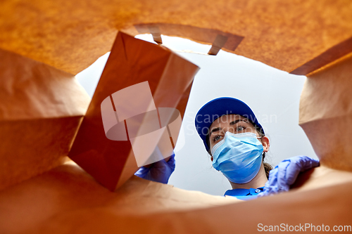 Image of delivery girl in gloves and mask with food in bag