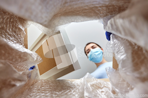 Image of woman in mask opening parcel box with photo frame