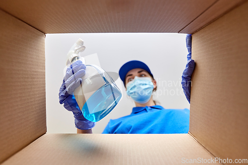 Image of woman in mask packing cleaning supplies in box