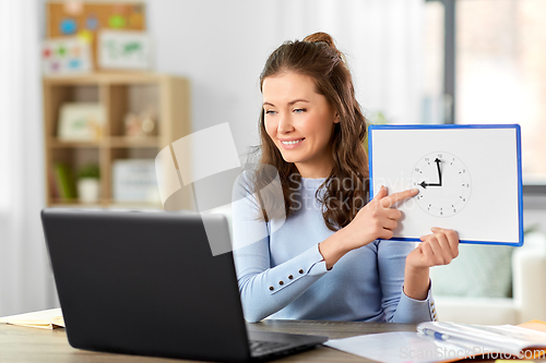 Image of teacher with clock having online class at home