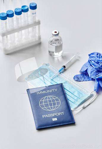 Image of immunity passport, mask, syringe, vaccine on table