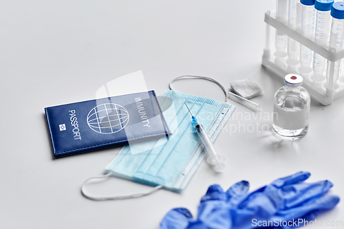 Image of immunity passport, mask, syringe, vaccine on table