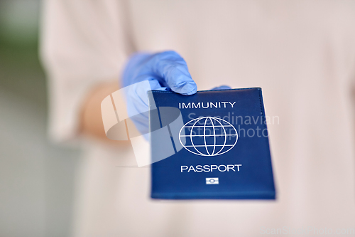 Image of woman in glove holding immunity passport