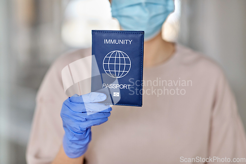 Image of woman in mask and gloves holding immunity passport