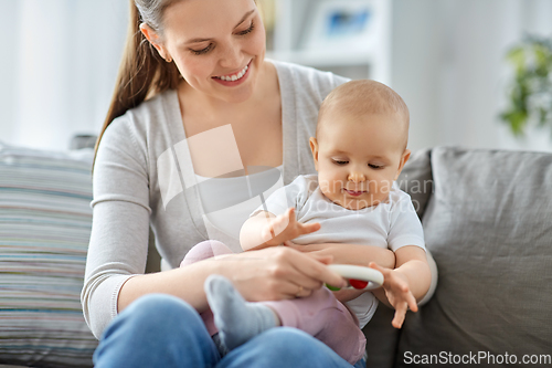 Image of mother and little baby playing with rattle at home