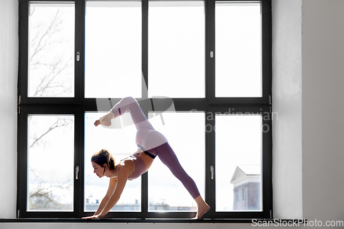 Image of woman doing yoga exercise on window sill at studio