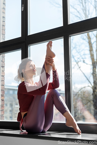 Image of woman doing yoga exercise on window sill at studio