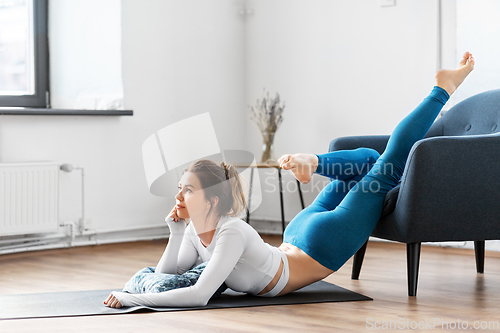 Image of young woman stretching and doing yoga at home