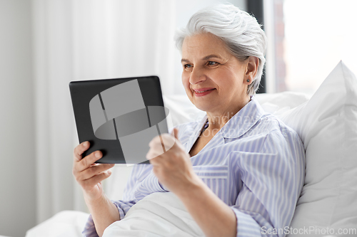 Image of senior woman with tablet pc in bed at home bedroom