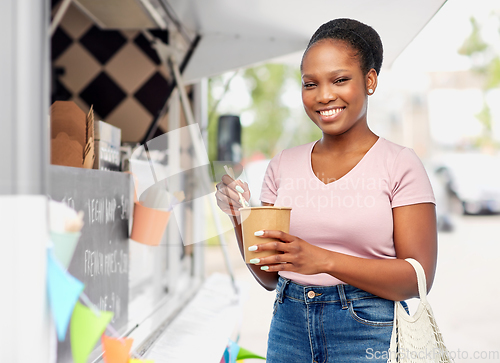 Image of happy woman eating wok over food truck