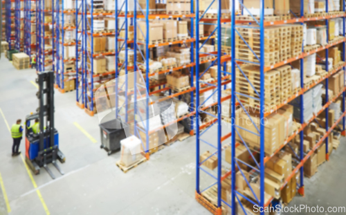 Image of Blur warehouse background. Above view of warehouse workers moving goods and counting stock in aisle between rows of tall shelves full of packed boxes
