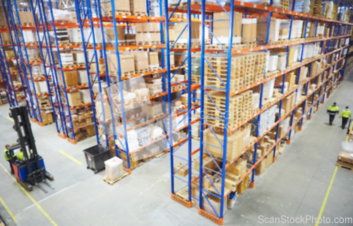 Image of Blur warehouse background. Above view of warehouse workers moving goods and counting stock in aisle between rows of tall shelves full of packed boxes