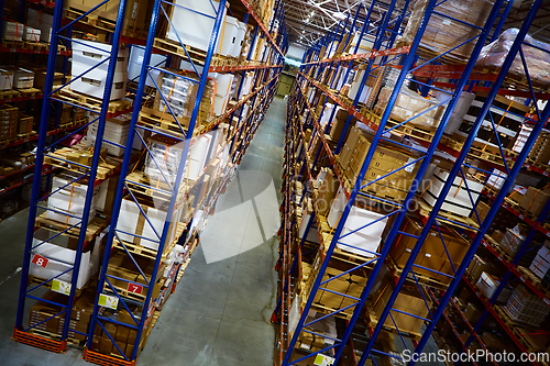 Image of Huge distribution warehouse with high shelves and loaders.