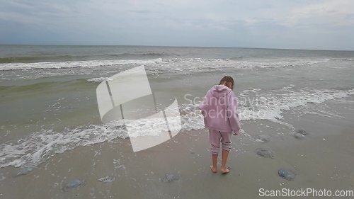 Image of Little kid girl plays on beach shallow water line summer rest during vacations