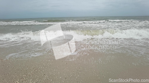 Image of Big tide waves with foam and splashes are crushing beach in slow motion.