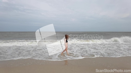 Image of Little kid girl plays on beach shallow water line summer rest during vacations