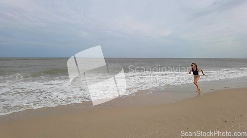 Image of Little kid girl plays on beach shallow water line summer rest during vacations