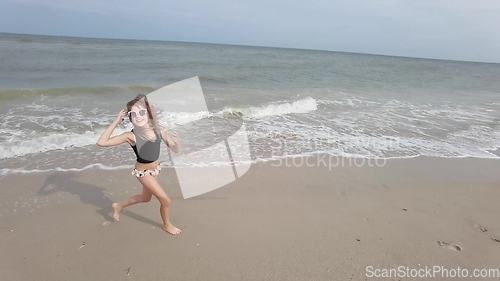 Image of Little kid girl plays on beach shallow water line summer rest during vacations